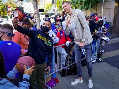 Dallas Mavericks center Kristaps Porzingis poses for a selfie with fans as the team leaves...