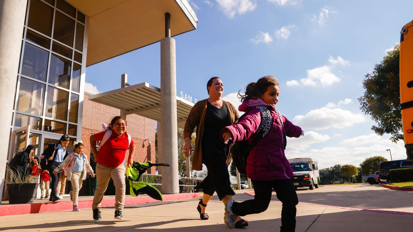 Principal Amanda Schmitter (center) walks elementary students to the bus from Grand Prairie...