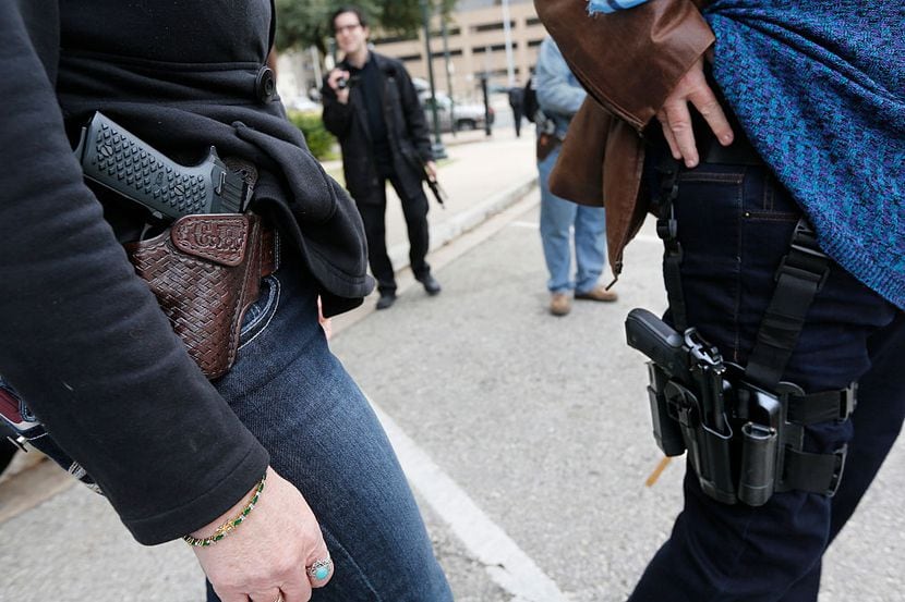 Dos personas muestran las pistolas que portan en fundas, durante una demostración frente al...
