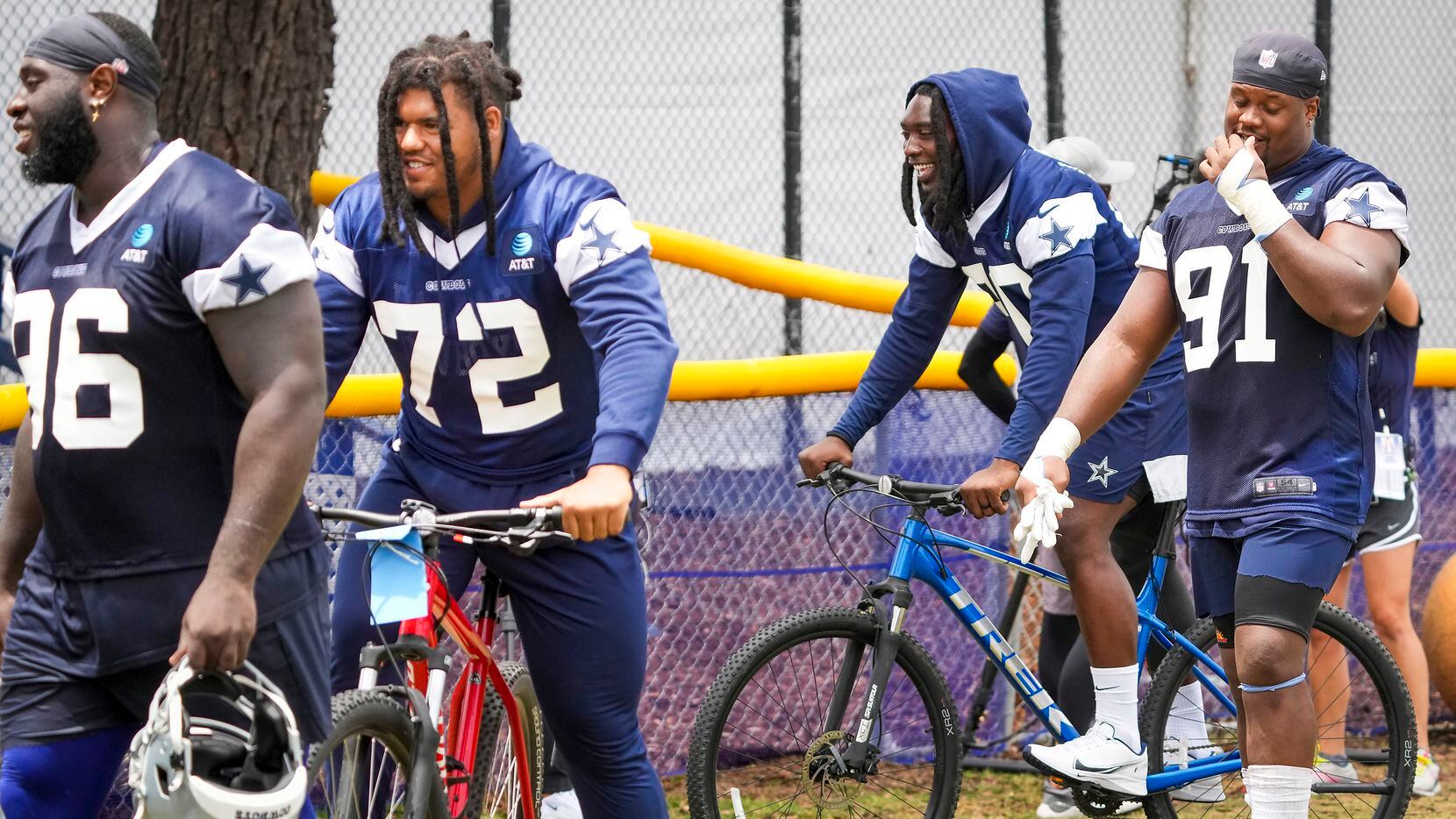 Dallas Cowboys defensive end DeMarcus Lawrence (90) and defensive tackle Trysten Hill (72) ride bicycles as they leave the field following a practice at training camp on Saturday, July 24, 2021, in Oxnard, Calif.