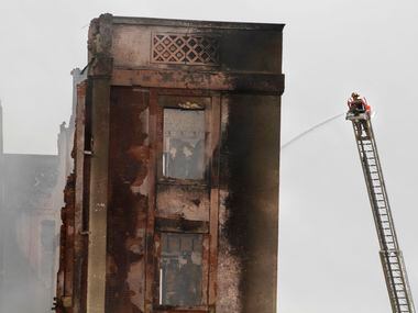A Dallas Fire-Rescue team member sprays water from atop a ladder on the Ambassador Hotel...