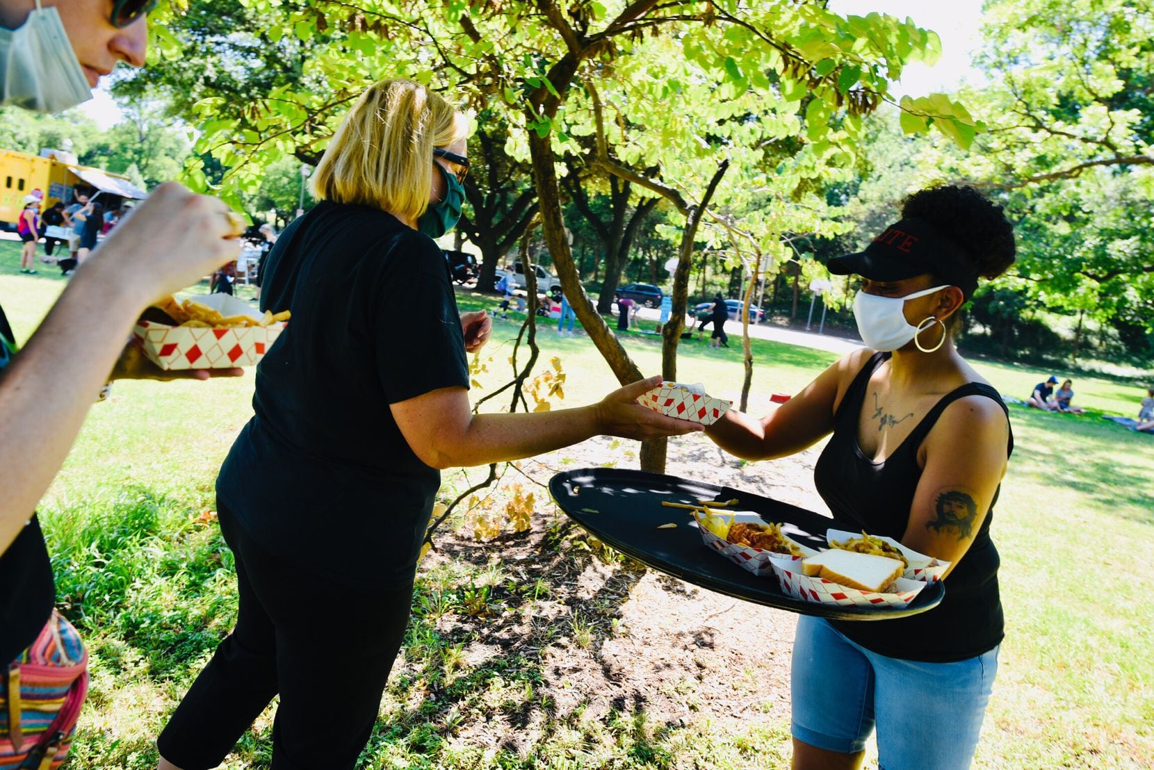 Volunteer Melinda Jones (right) hands out food from Hall’s Honey Fried Chicken during the...