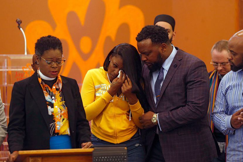 L'Daijohnique Lee (center) wipes away tears as she is consoled by her attorney, Lee Merritt...