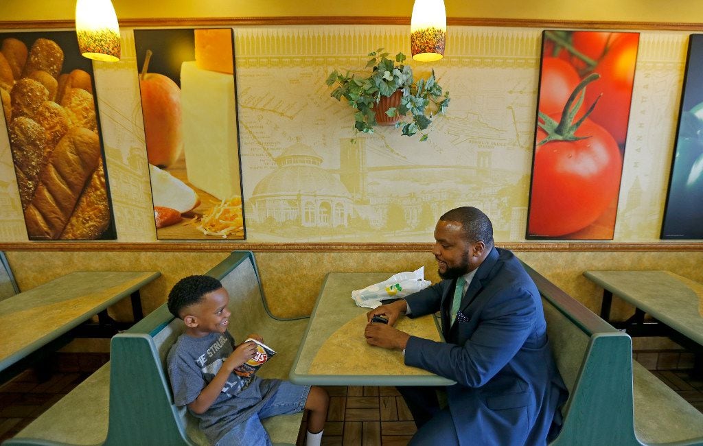 Attorney Lee Merritt (right) and his 7-year-old son Stacy Merritt, Jr., eat snacks and...