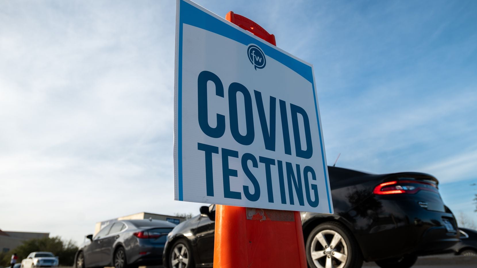 Signage is on display as motorists wait for a COVID-19 test in the parking lot of...