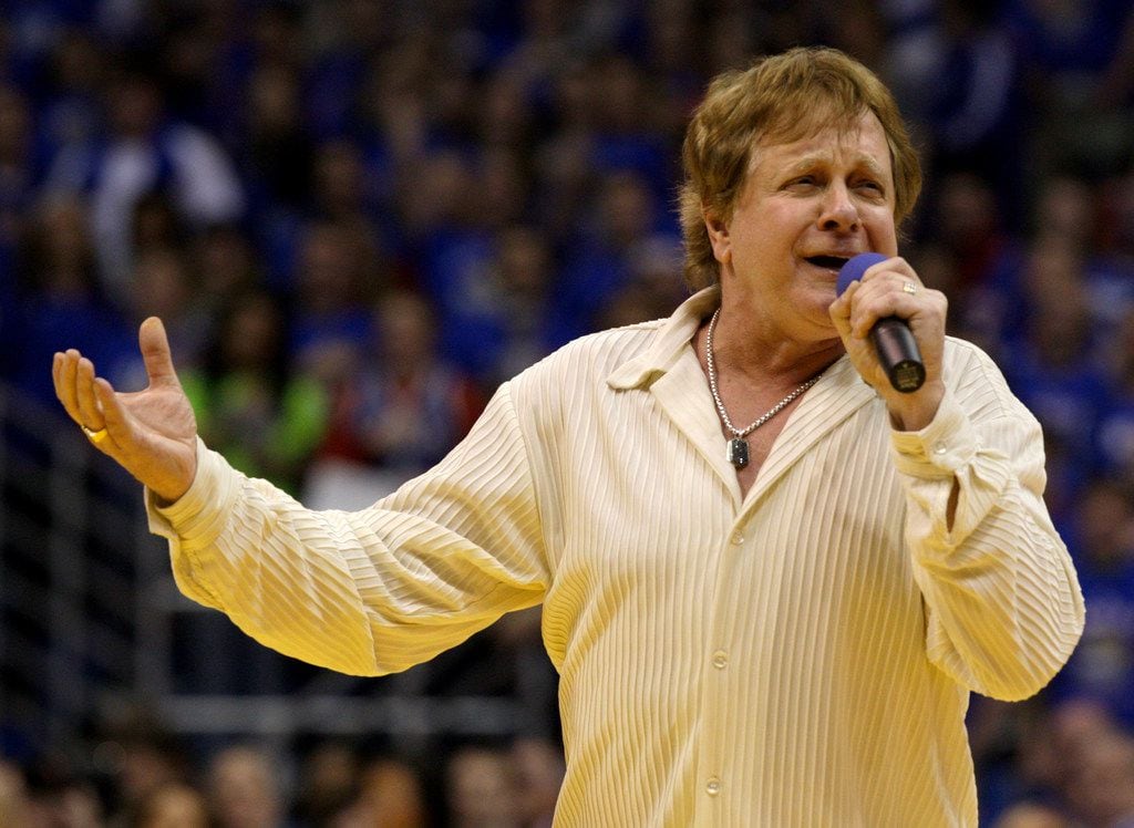 In this Jan. 25, 2010 file photo, Eddie Money sings the national anthem before an NCAA college basketball game between Kansas and Missouri in Lawrence, Kan.  Family members have said Eddie Money has died on Friday, Sept. 13, 2019. (AP Photo/Charlie Riedel, File)