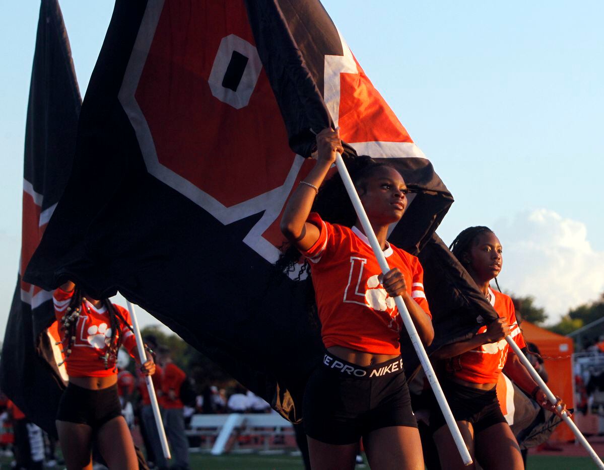 Lancaster trackster Kialia Claiborne, center, leads fellow track members as they run flags...