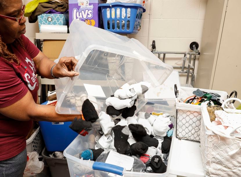 Philicia Turner, a worker at Carter's House, empties a storage bin of socks into another at...