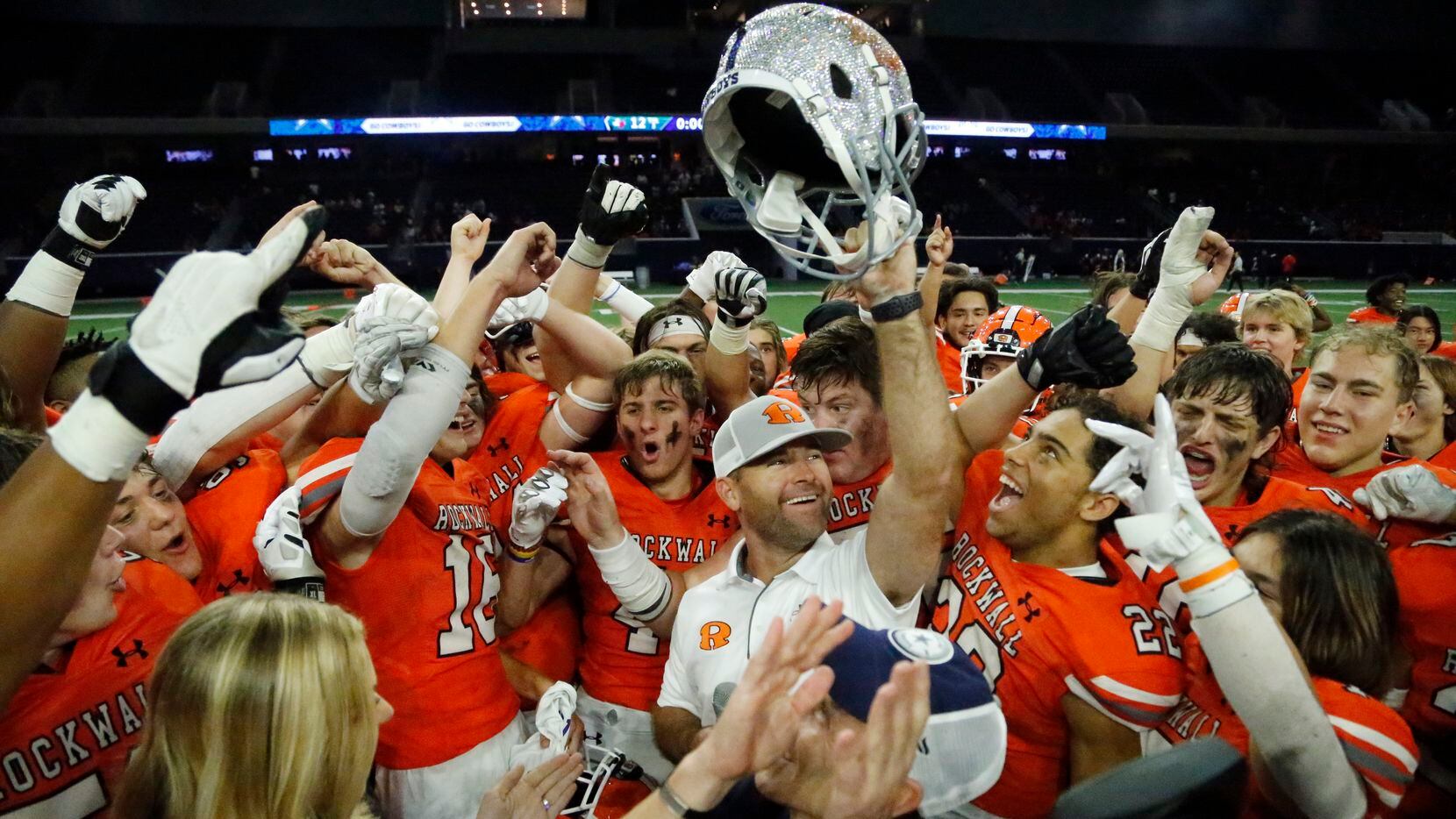 Surrounded by his team, Rockwall High School head coach Trey Brooks holds up the trophy for...