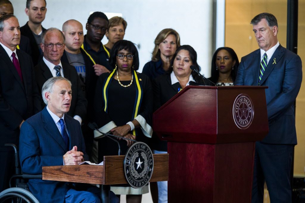 Texas Gov. Greg Abbott (left) and Dallas Mayor Mike Rawlings (right) speak during a press conference on Friday at Dallas City Hall in downtown Dallas, Texas. They stood in front of a group of Dallas city councilmen, state representatives, state senators and Texas Attorney General Ken Paxton (standing on far left). They made comments about a shooting on Thursday in downtown Dallas that targeted police officers and left five people dead and seven more injured.
