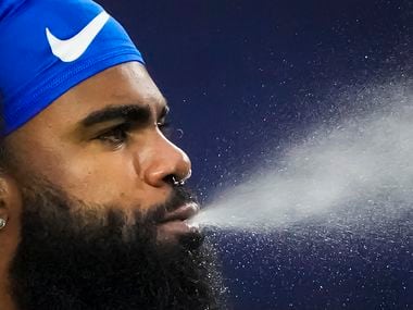 Dallas Cowboys running back Ezekiel Elliott blows water as the team warms up before an NFL football game against the Carolina Panthers at AT&T Stadium on Sunday, Oct. 3, 2021, in Arlington.