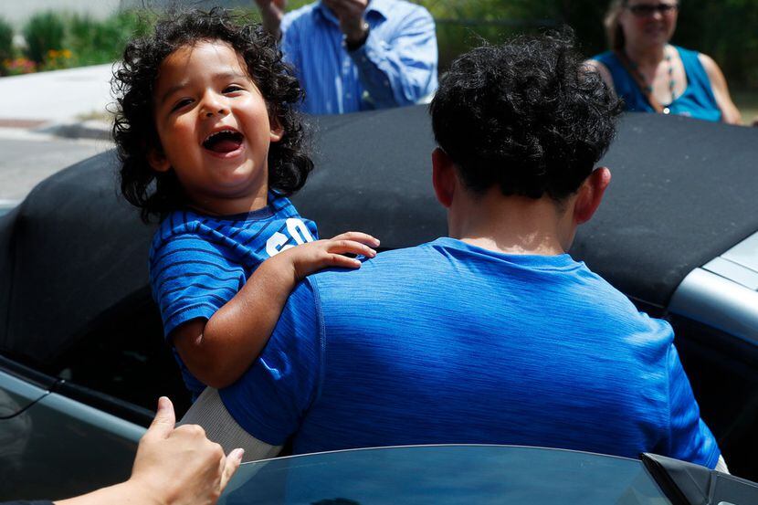 Ever Reyes Mejia, of Honduras, carries his son to a vehicle after being reunited and...