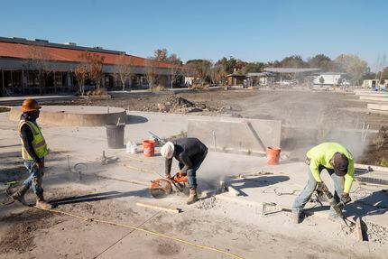 Construction workers cut through concrete as they shape the walkable areas during renovation...