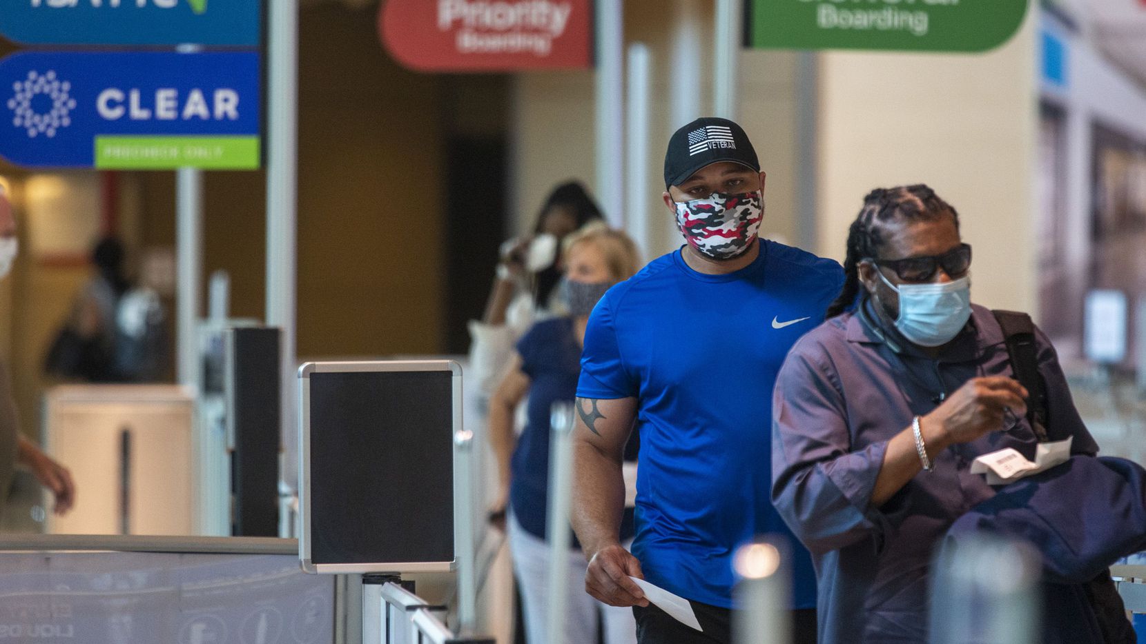 Masked passengers walk to the security checkpoint at Dallas Love Field airport in Dallas on a recent morning.