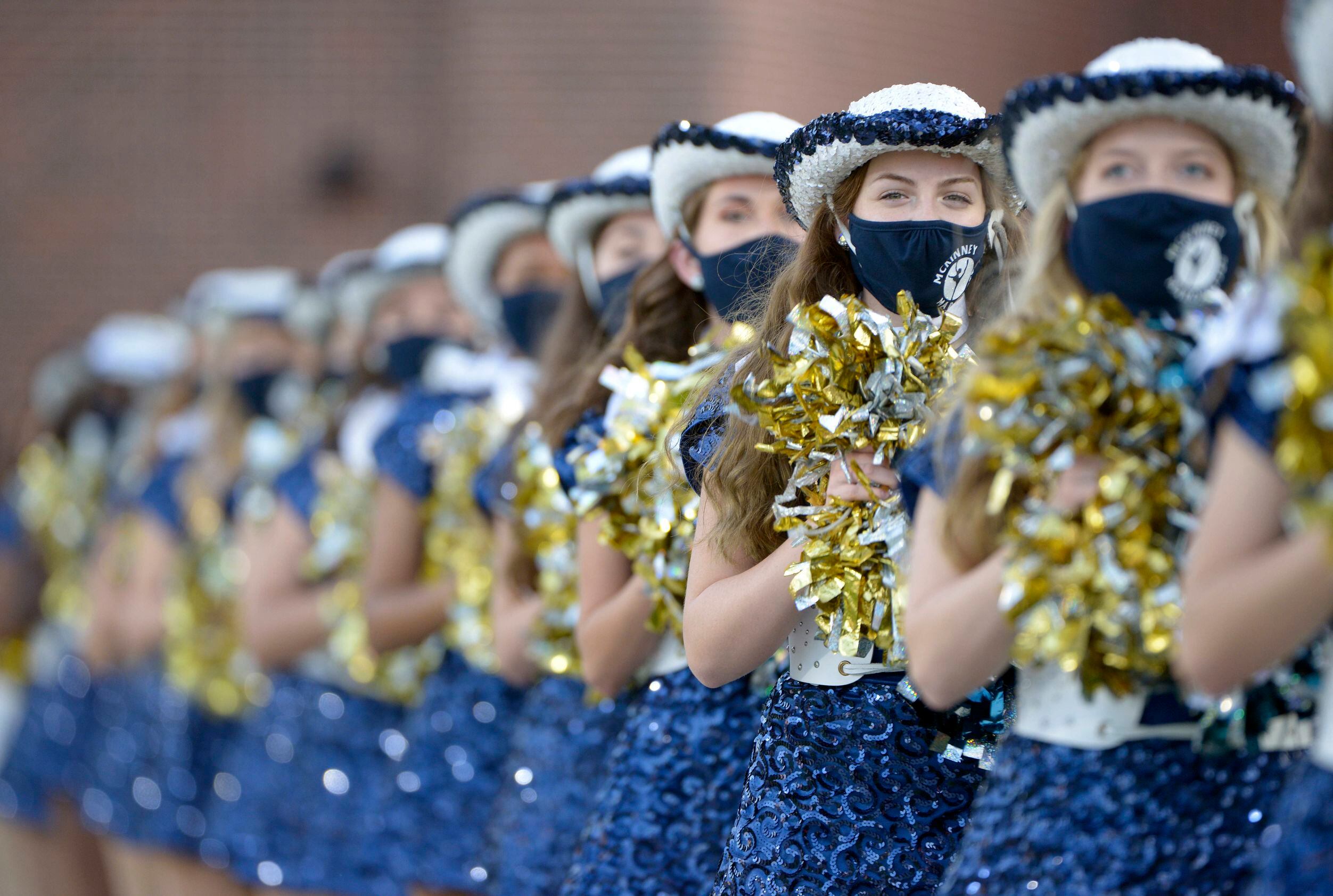 The McKinney Marquettes line the field before a high school football game between Plano and...