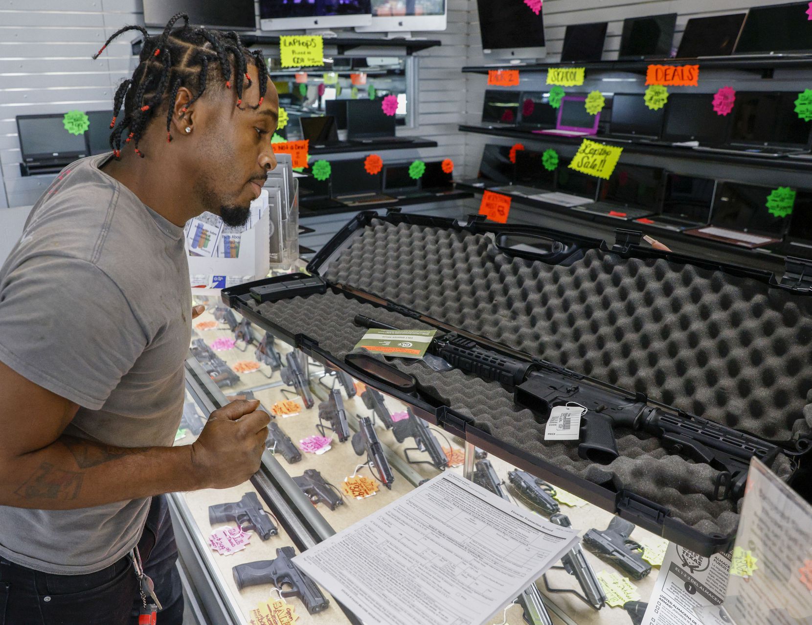 Brian Benford, 31, looks at a Colt rifle while shopping at Uncle Dan’s Pawn Shop in...