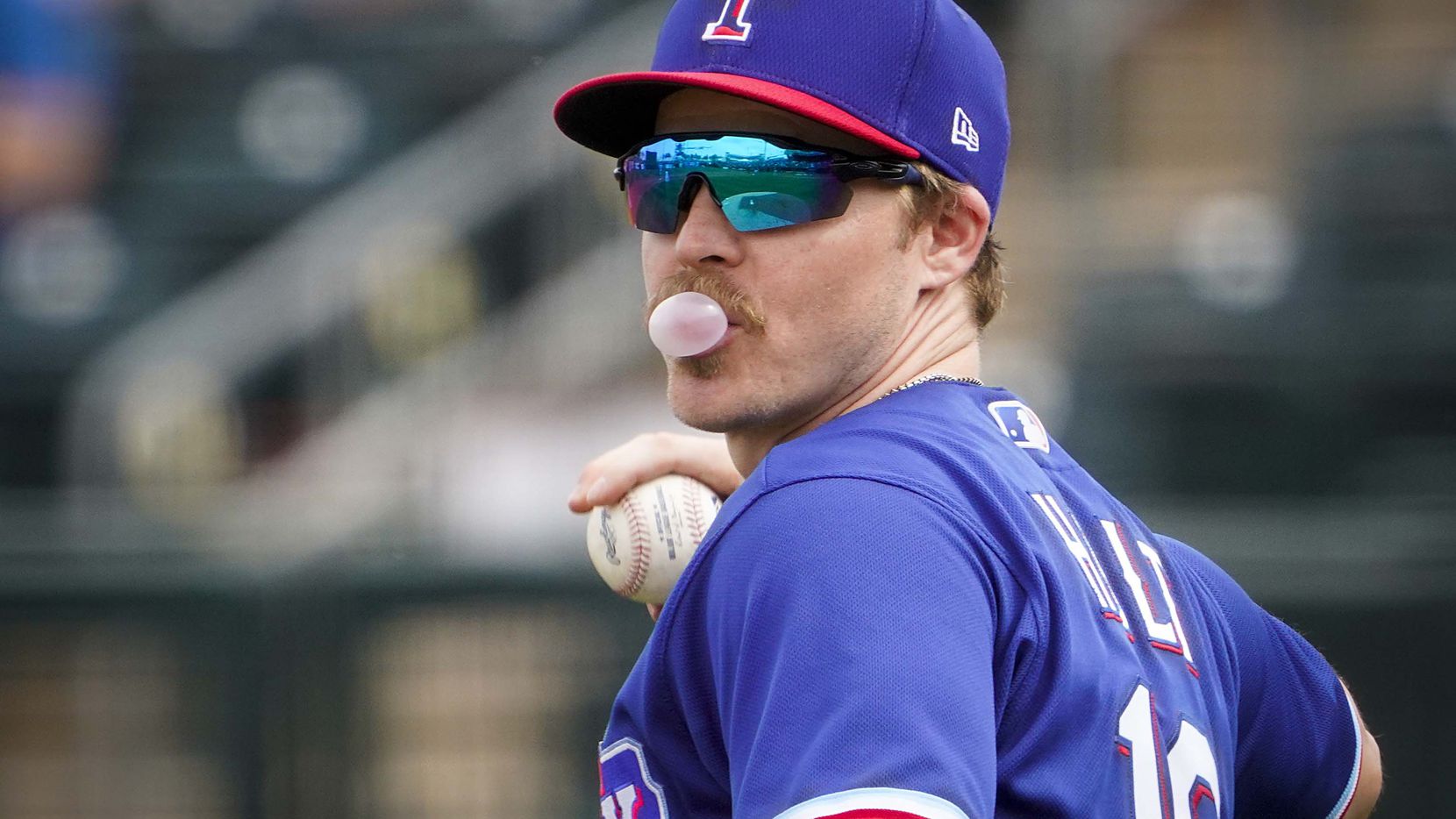 Texas Rangers second baseman Brock Holt blows a bubble as he brings the ball back into the...