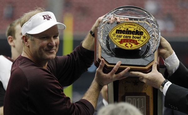 Texas A&M Aggies interim head coach Tim DeRuyter raises the Meineke Car Care Bowl of Texas trophy following the Aggies' 33-22 win over the Northwestern Wildcats.