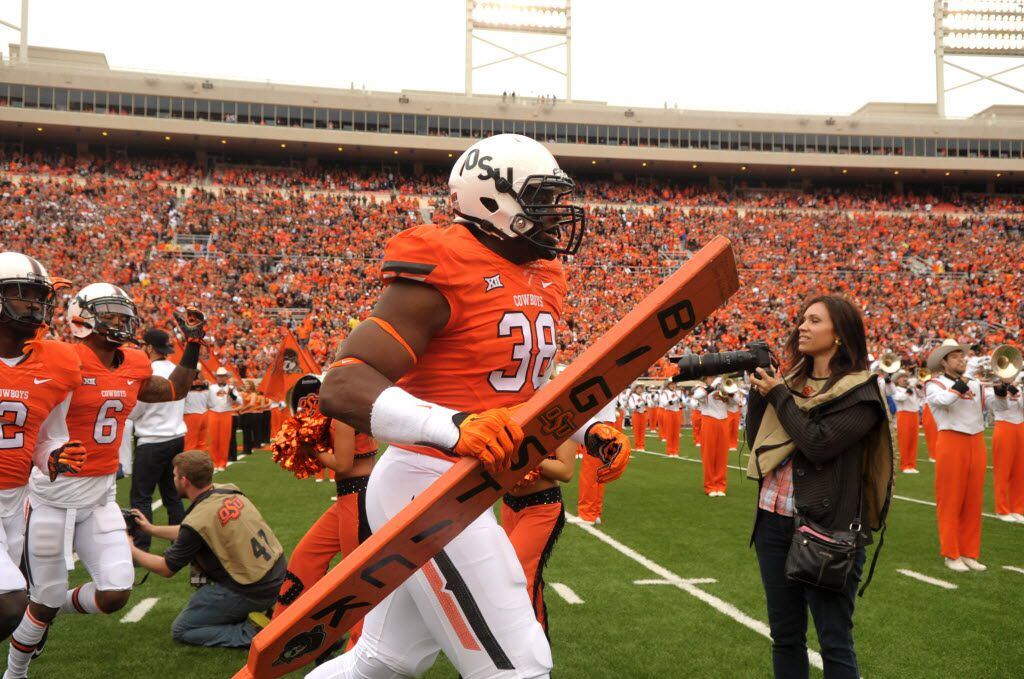 Oklahoma State defensive end Emmanuel Ogbah (38) carries the team's "Big Stick" onto the field at the start of an NCAA college football game between Kansas and Oklahoma St in Stillwater, Okla., Saturday, Oct. 24, 2015.(AP Photo/Brody Schmidt)