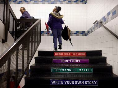 Bus driver Schrildea Glover (left) and first grader Kensley Kennedy ascend the stairs to her...
