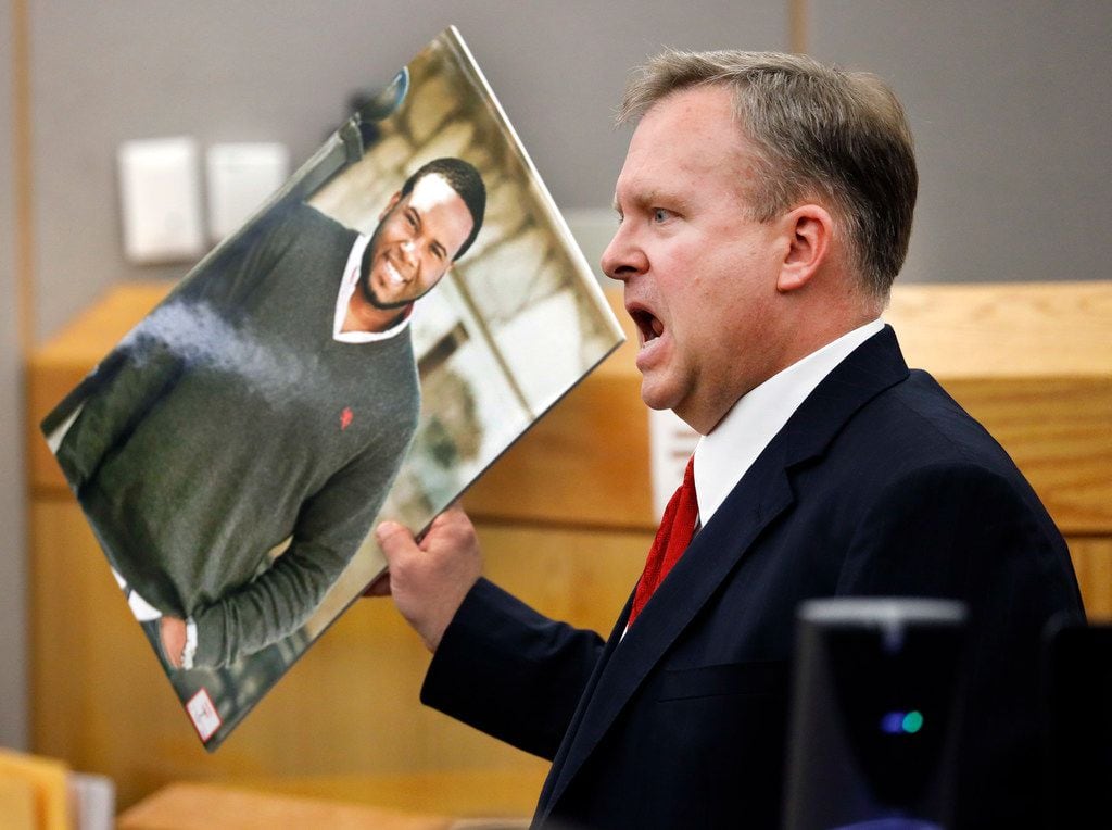 Assistant District Attorney Jason Hermus waves a photo of Botham Jean at the jury as he...