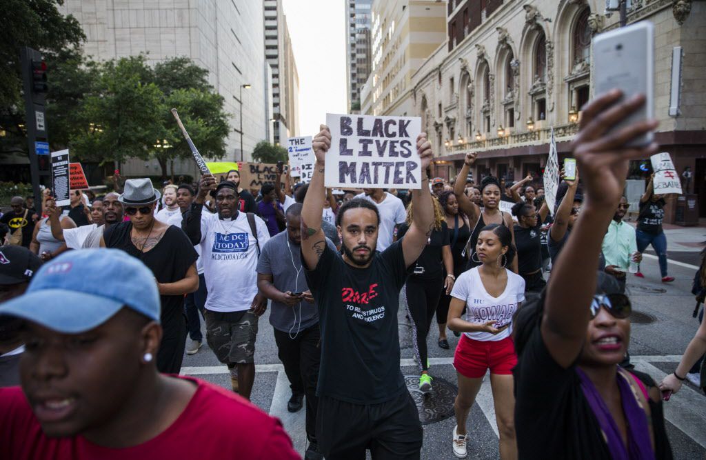 Protesters march through downtown Thursday before a gunman later identified as Micah X....