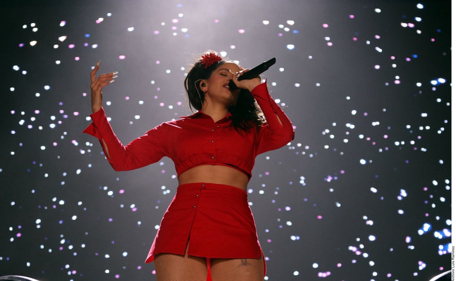 Rosalía cantando en un concierto con un atuendo rojo.