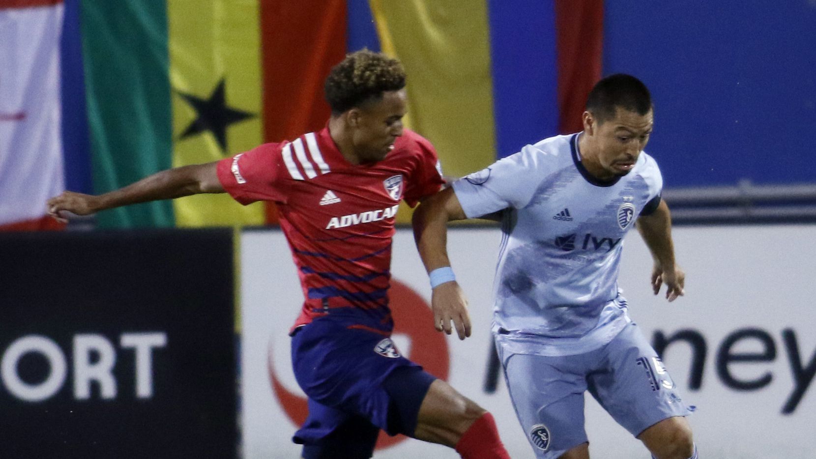 FC Dallas' Bryan Reynolds (14), left, challenges Sporting KC's Roger Espinoza (15) who works to maneuver the ball inside during first half action. The two teams, both members of the Western Conference of MLS, played their match at Toyota Stadium in Frisco on October 14, 2020.