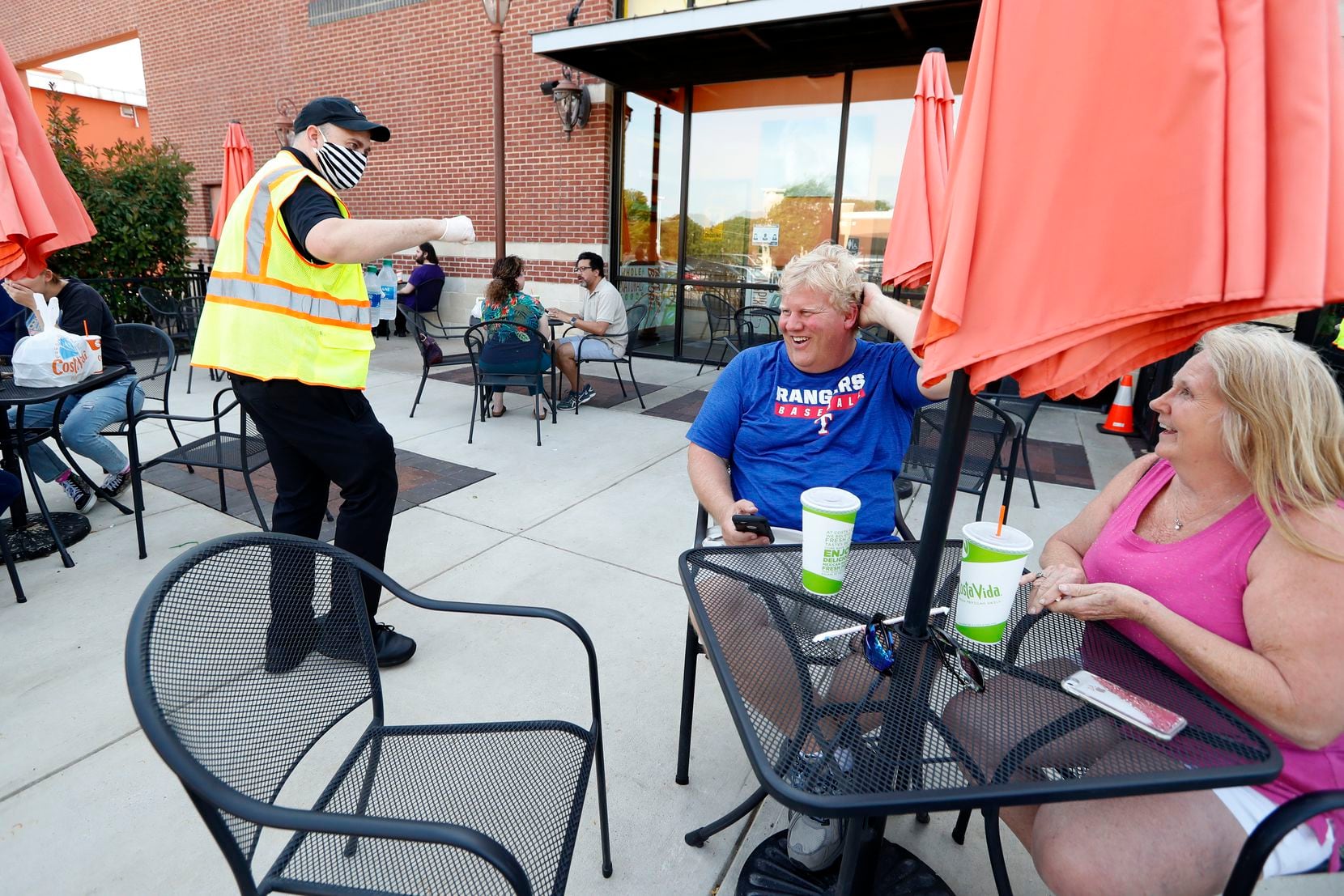 General manager Jay Norman, left, talks with Chad Steenwyk, center, and his wife Glenda, right, as the two dine outdoors on the patio at Costa Vida, a Mexican restaurant in Colleyville, Texas, Monday, April 27, 2020. The city of Colleyville relaxed rules in place due to COVID-19, allowing local restaurants to open up their patio to customers for dinning. (AP Photo/Tony Gutierrez)