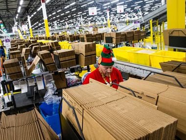 Donning an elf's hot, Jeffrey Tucker fills a box with air bags to cushion packages.