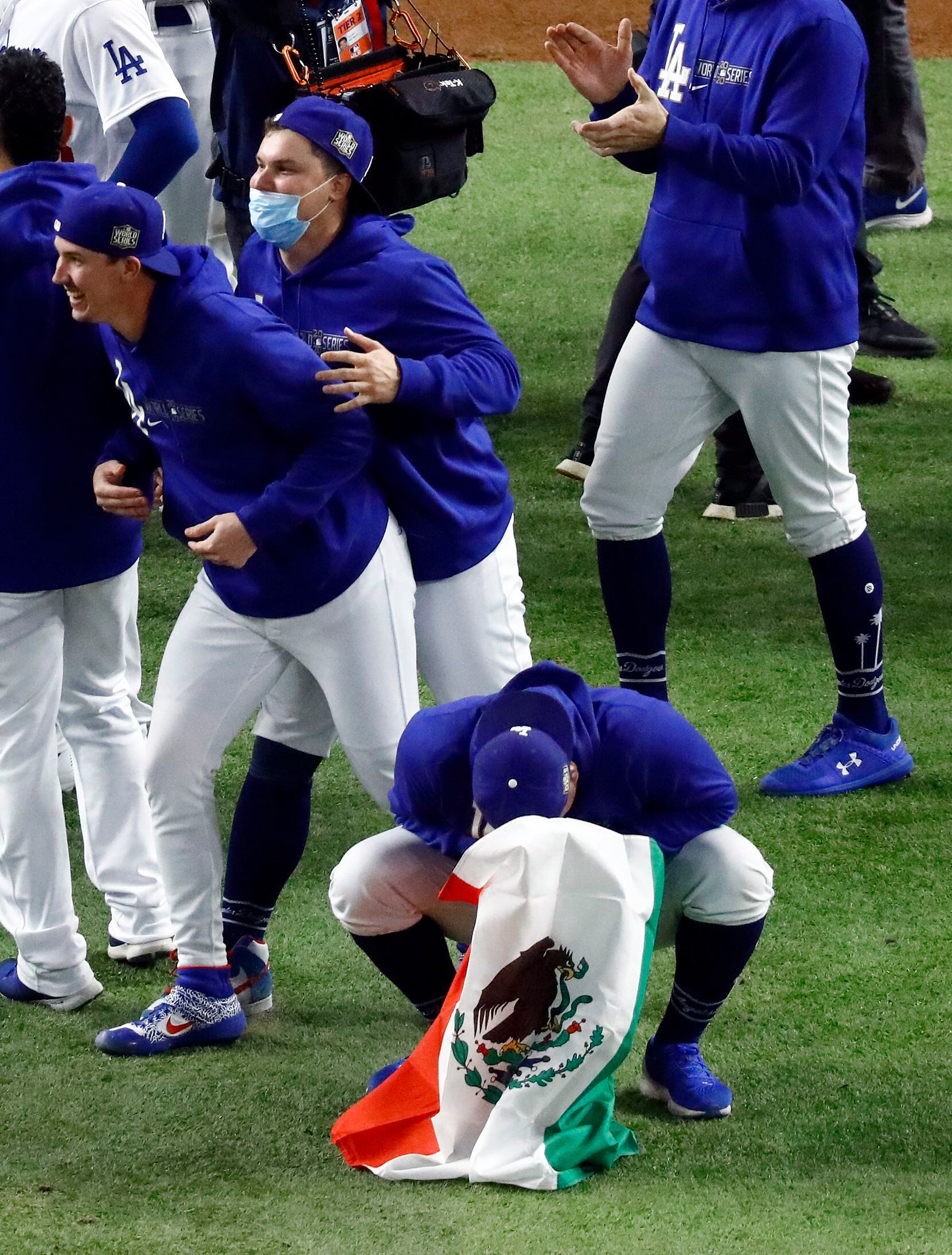 Los Angeles Dodgers starting pitcher Victor Gonzalez (with Mexican flag) is overcome with...
