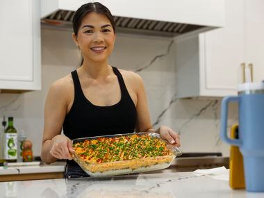 Alissa Nguyen smiles at the camera while holding a tray of food.