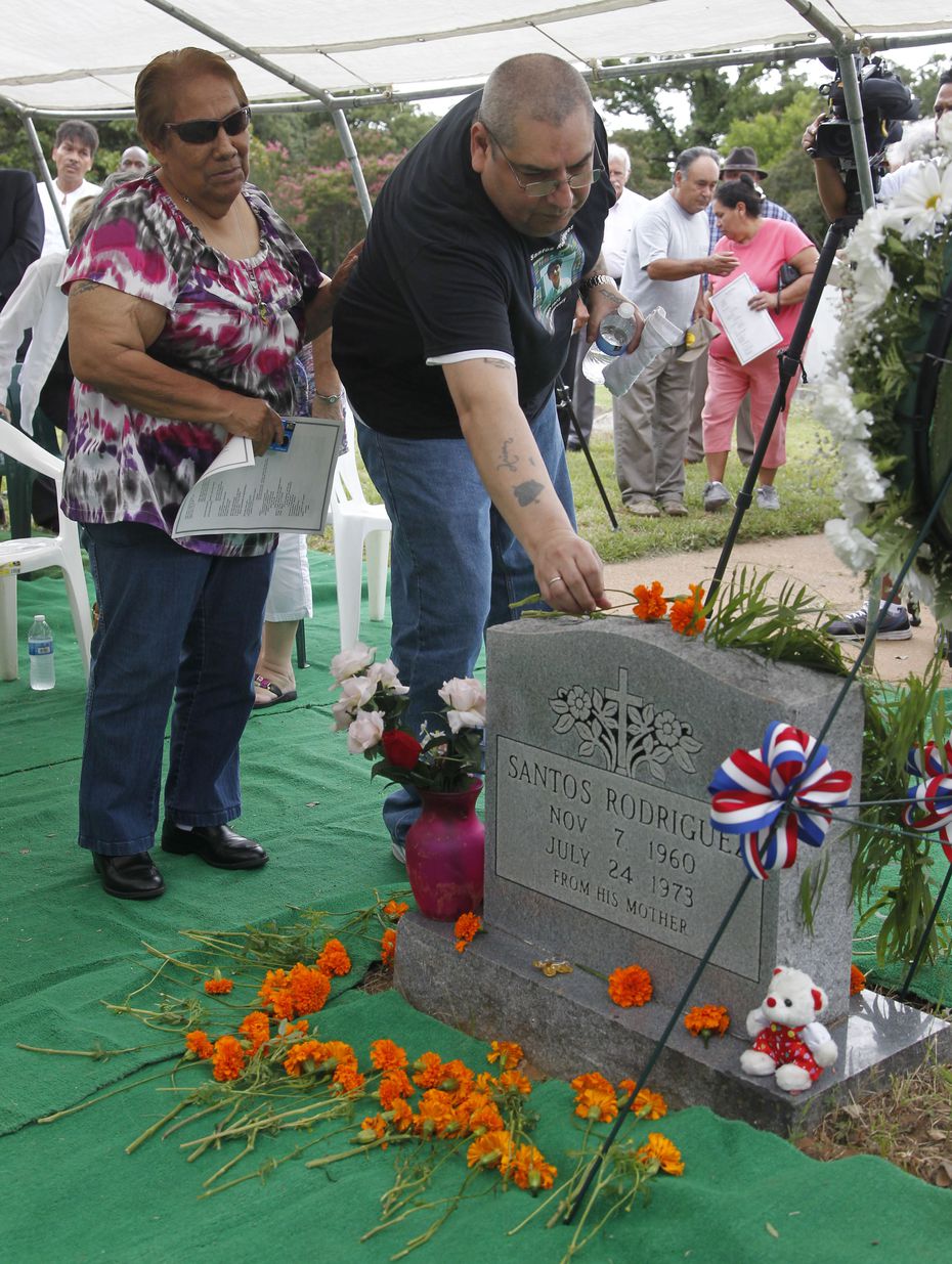 Bessie Rodriguez and her son David Rodriguez place a marigold on the grave of her son,...