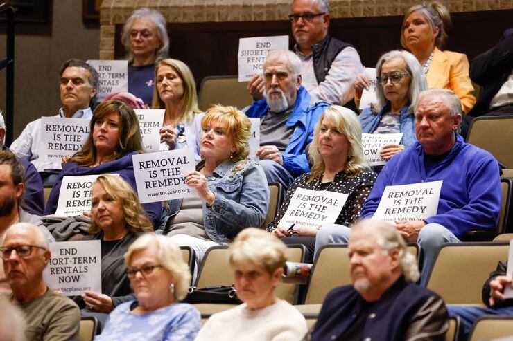 Those opposed to short-term rentals hold signs up throughout the public comment portion of a...