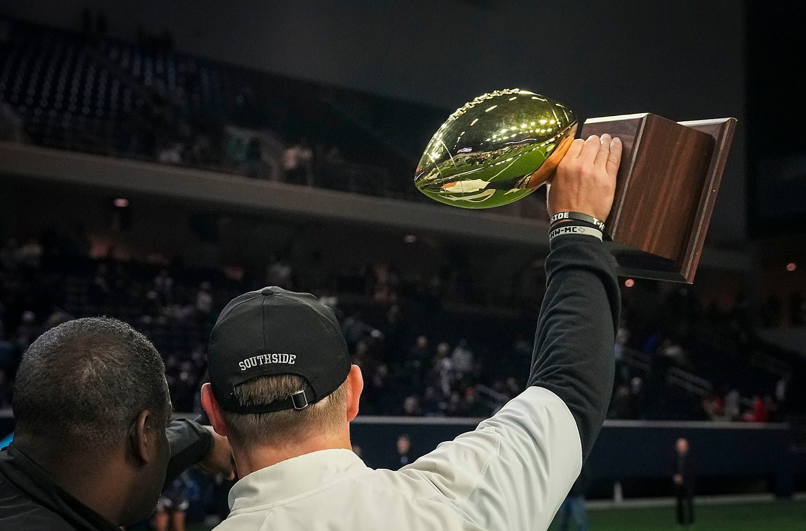 Denton Guyer head coach Reed Heim holds up the game trophy as he celebrates with his players...