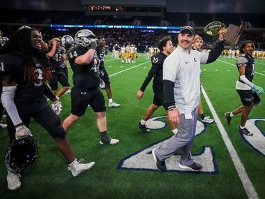 Denton Guyer head coach Reed Heim holds up the game trophy as he celebrates with his players...