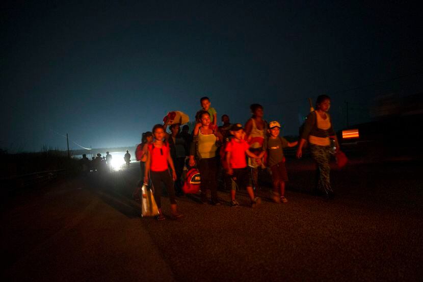 Una familia camina junto a otros migrantes centroamericanos en una caravana de miles de...