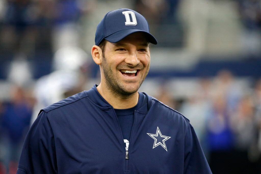 Dallas Cowboys quarterback Tony Romo smiles as he talks with teammates on the field during...