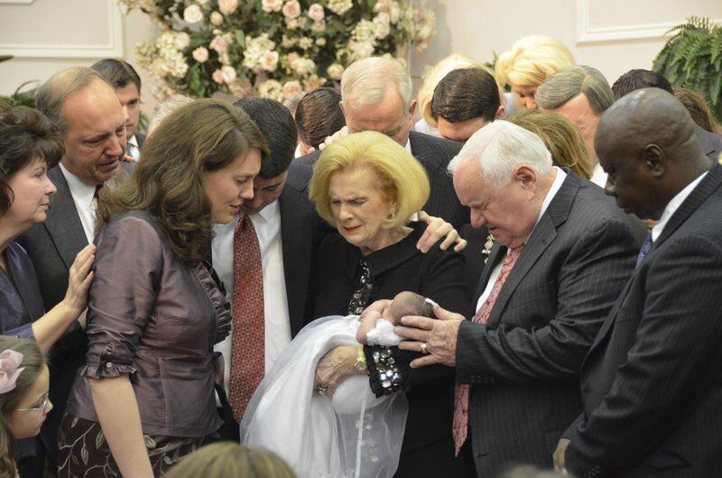 In this 2012 photo provided by a former member of the church, Word of Faith Fellowship leader Jane Whaley, center, holds a baby, accompanied by her husband, Sam, center right, and others during a ceremony in the church's compound in Spindale, N.C.