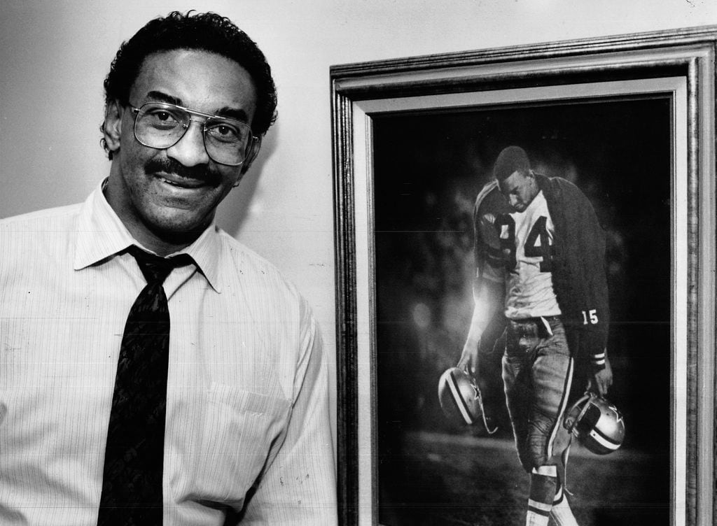 In a 1988 photo, former Dallas Cowboys star Pettis Norman stands next to a picture of himself that was taken at the end of the 1966 NFL Championship game against the Green Bay Packers at the Cotton Bowl. The Cowboys lost the game. The photo ran in Sports Illustrated and is hanging in his office.