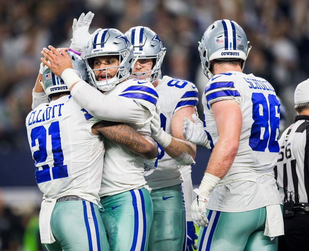Dallas Cowboys quarterback Dak Prescott (4) hugs running back Ezekiel Elliott (21) after a...
