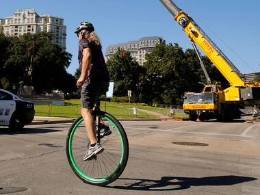 A unicyclist pedals past the Robert E. Lee statue as they attempted to remove it from Robert...