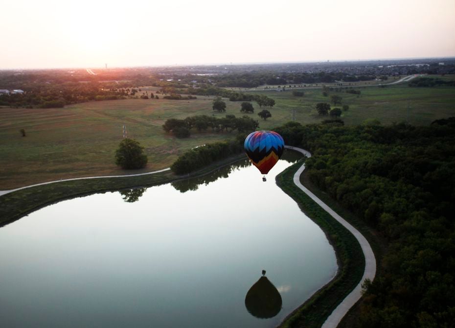 A balloon touches down over the water during a media flight before the Plano Balloon Festival  at Oak Point Park.