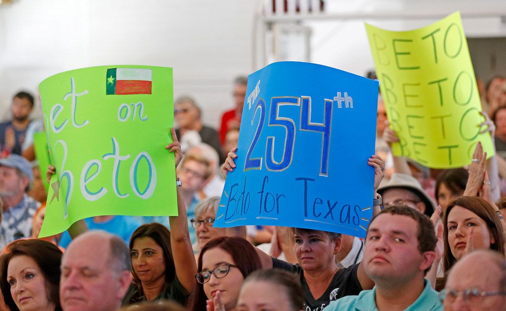 Supporters hold up signs while Congressman Beto O'Rourke speaks during a town hall at the...