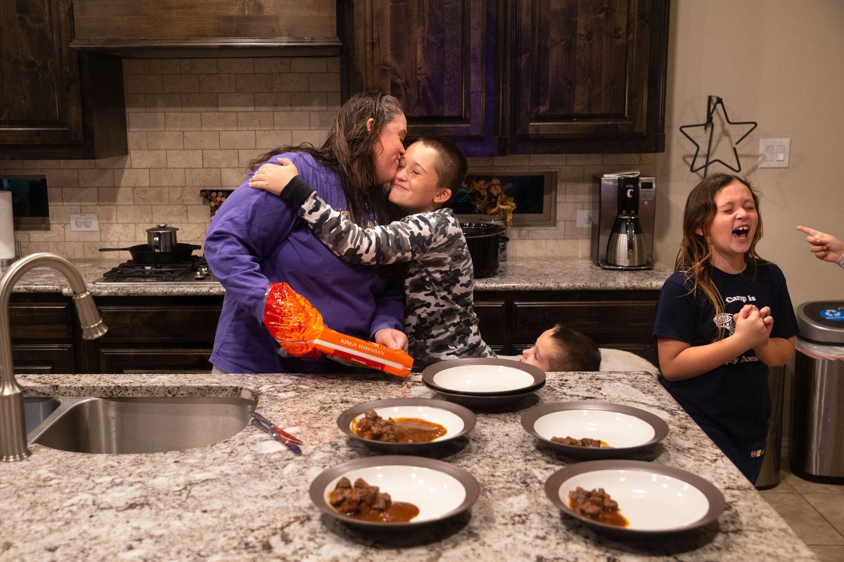 Samantha Rowley kisses her 9-year-old son, Emery, as Jaxson, 4, and Emily, 8, line up for hugs just before dinnertime at the family's home in Frisco. On many nights, Rowley makes it home from work not long before her four children's bedtime.