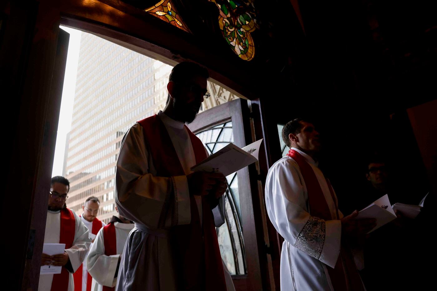 Priests are silhouetted as they enter the church during a memorial mass for late Pope...