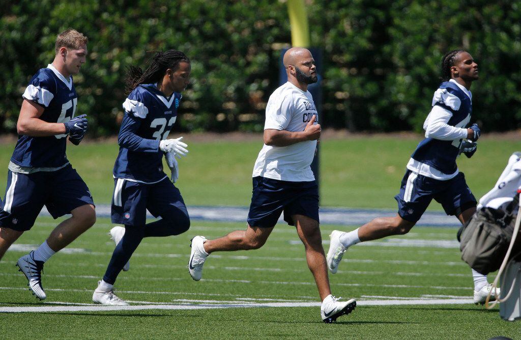 Kris Richard (center), new secondary coach runs with players during the Dallas Cowboys...