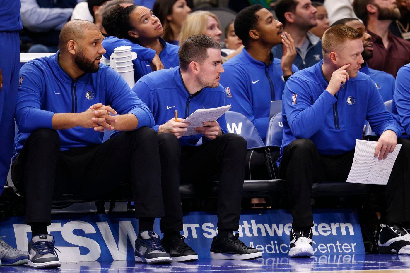 Dallas Mavericks assistant coach Greg St. Jean (center) watch the second half of an NBA game...