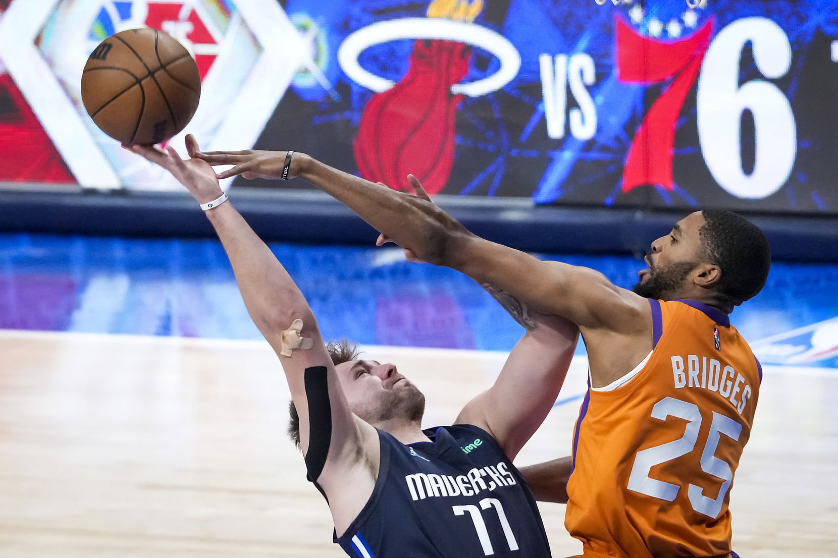 Dallas Mavericks guard Luka Doncic (77) is fouled by Phoenix Suns forward Mikal Bridges (25)...
