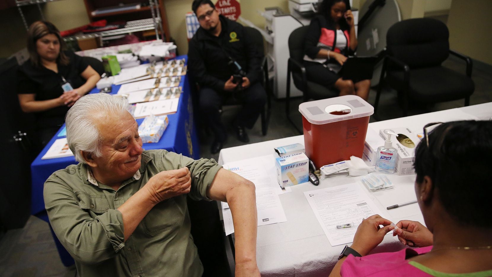 Gavino Saldivar, of DeSoto, Texas, lifts his sleeve up before receiving an influenza vaccine...